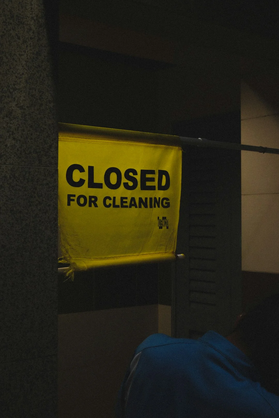 Anonymous male in yellow rubber gloves wiping foam from round mirror in bathroom